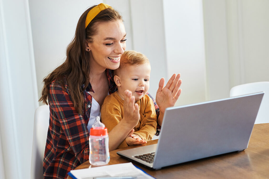Mutter und Baby vor dem Laptop, beim arbeiten um die Elternzeit im Lebenslaufs zu umgehen.