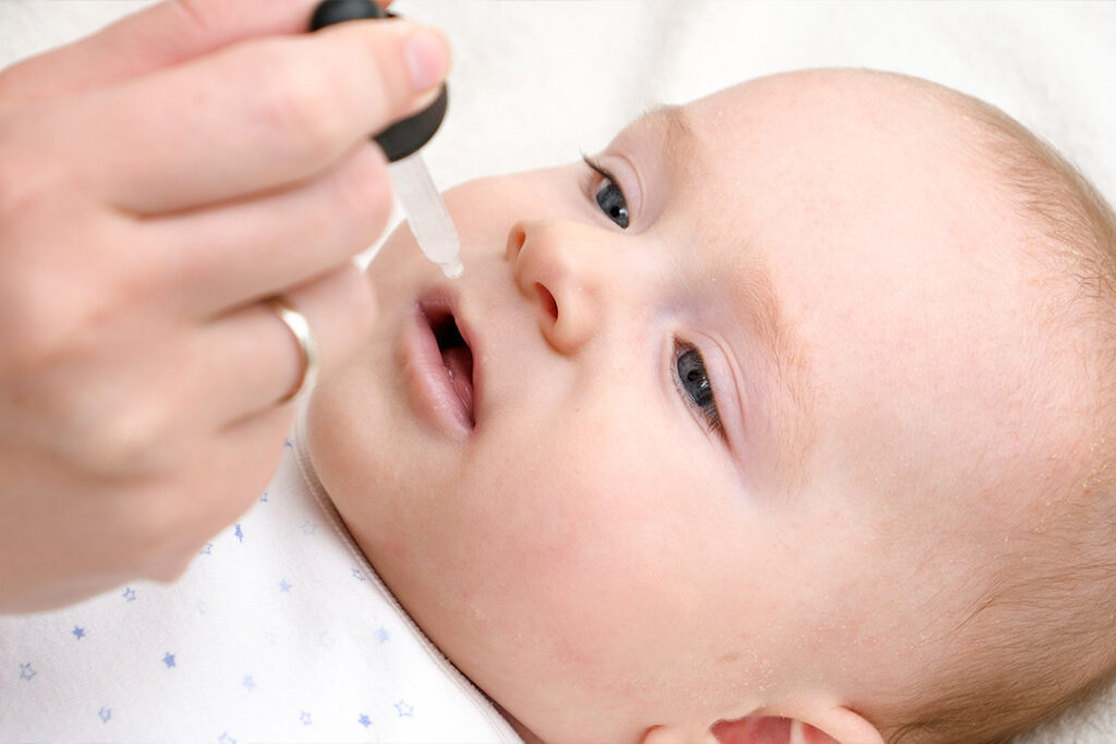 Eine Mutter träufelt dem eigenen Baby eine Kochsalzlösung für Babys in die Nase. - Schritt 5: Gib behutsam einige Tropfen der Kochsalzlösung in beide Nasenlöcher deines Babys, um Sekrete und Schleim aus den Nasengängen zu spülen.