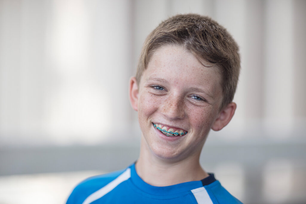 MamaGrow Beitragsbild - Portraitbild eines Jungen mit einer Brackets Zahnspange als Symbolbild für das Thema Zahnspange für Kinder - Braucht mein Kind eine Zahnspange?