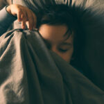 Einschlafhilfen für Kinder - Mamagrow FAQ-Beitrag - Ein kleiner Junge unter der Bettdecke kann nicht einschlafen.
