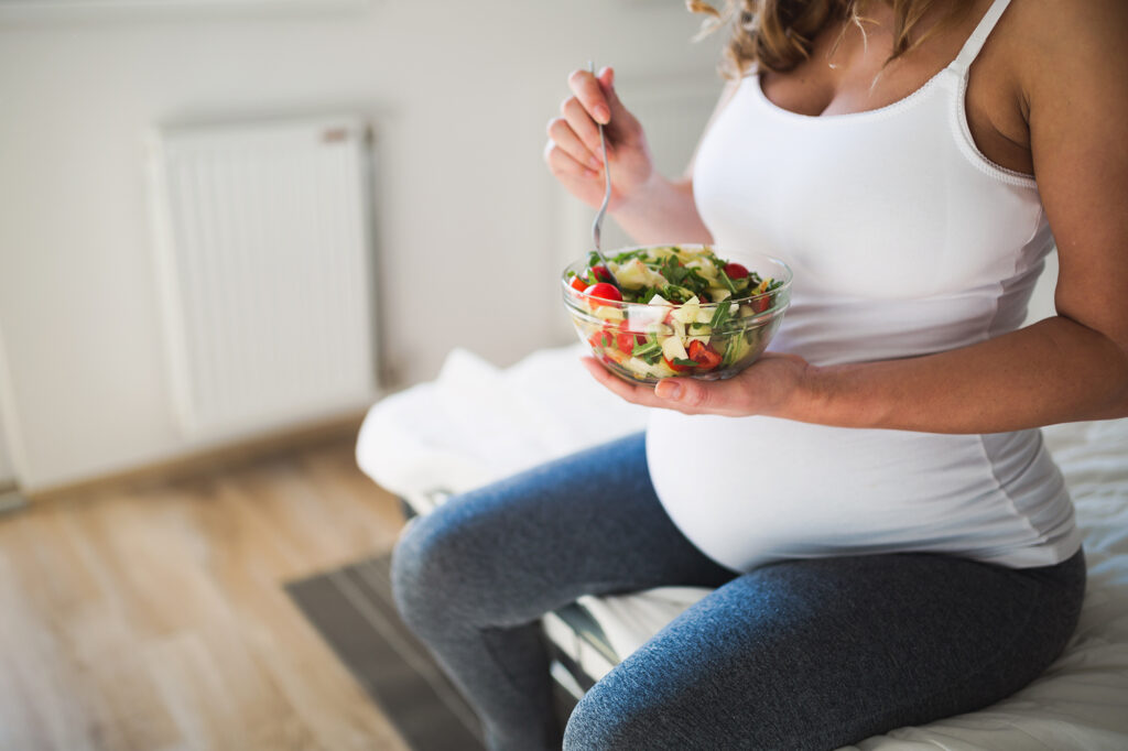 Rezepte für stillende Mütter - Eine schwangere Frau isst einen Salat als Sinnbild für eine Stillende Frau.