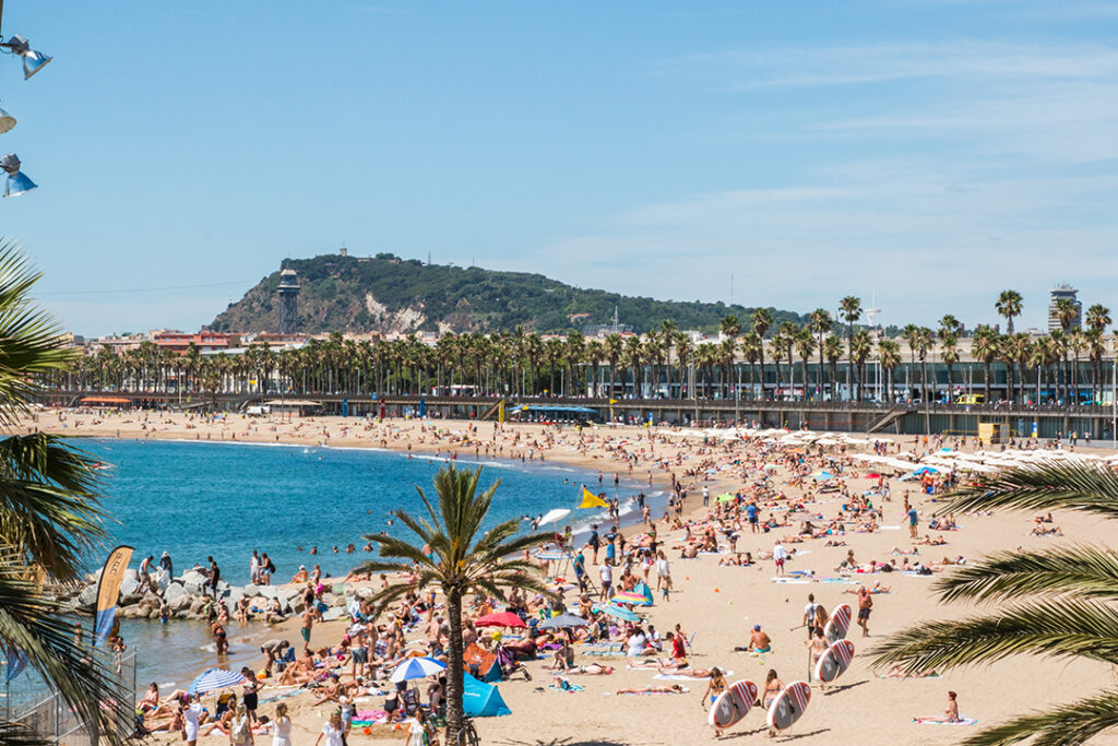 Barcelona mit Kindern - Strand von Barcelonetta in Barcelona, Spanien, an einem sonnigen Tag voller Menschen.